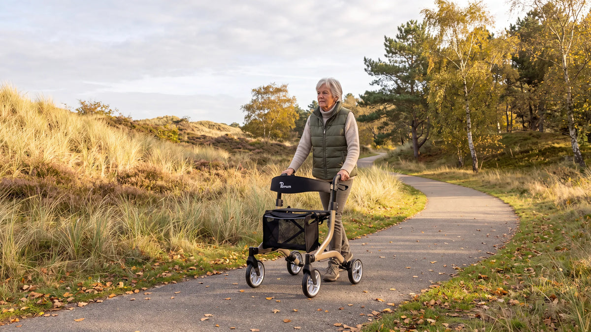 Parvum SuperLight Plus in champagne op een duinpad; een vrouw met grijs haar loopt met de rollator.