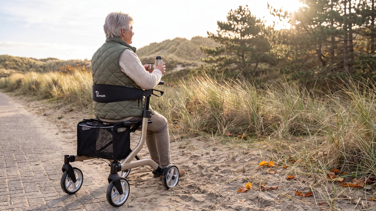 Parvum SuperLight Plus in champagne aan de duinrand in tegenlicht; een vrouw zit op de rollator met een kop thee.