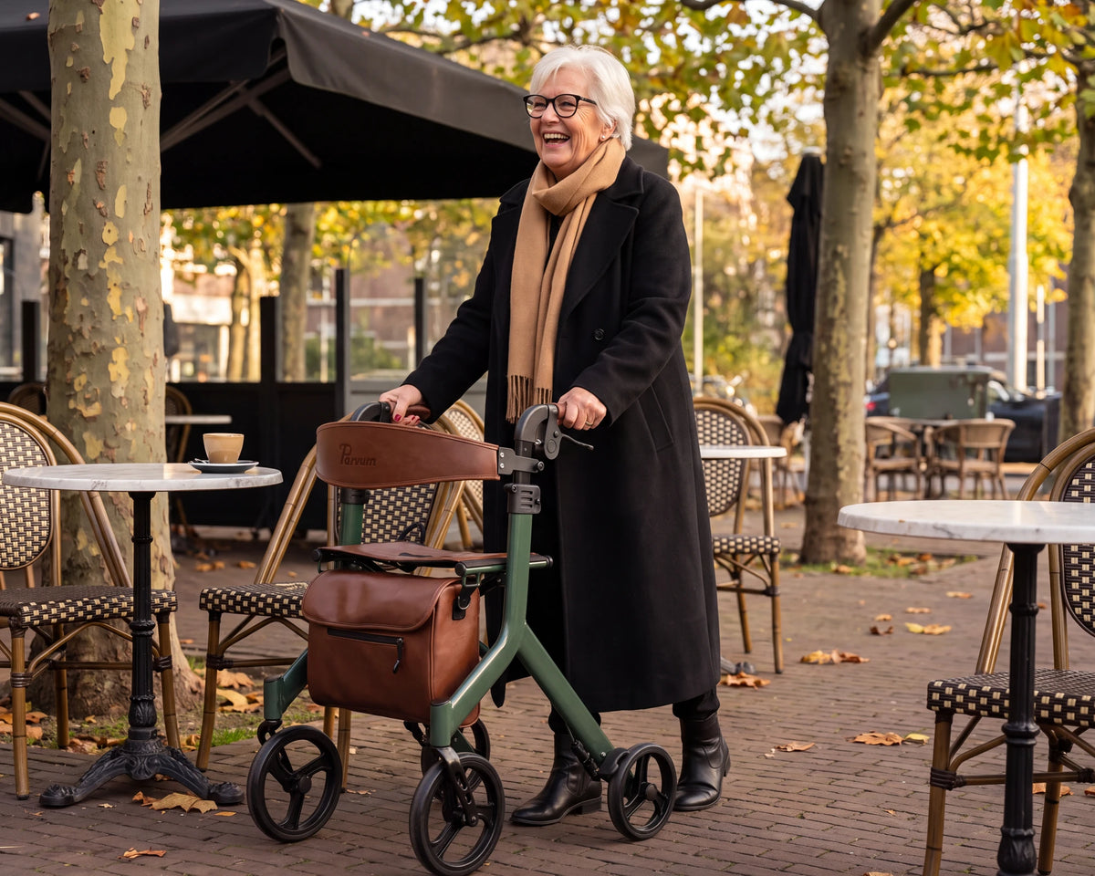 Parvum Vesta in moss green on a terrace; a woman with white hair and glasses laughs, her hands on the handles.